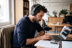 Ein Journalist mit Kopfhörern arbeitet an einer Interview-Aufnahme.